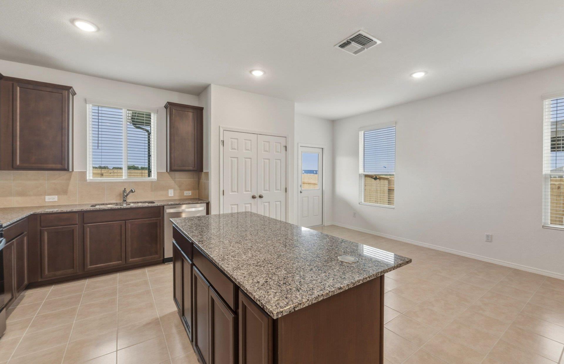 545 Henry Milton Road Georgetown, TX 78626 - Photo 5 of 33 Granite countertops and clean tile floors highlight this open-concept kitchen and adjacent dining area.