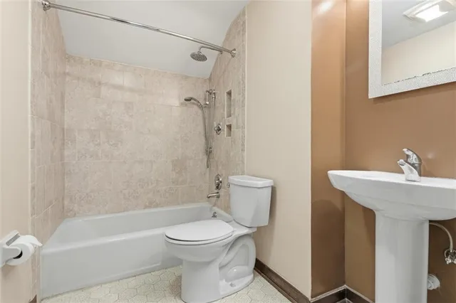 a bathroom with a toilet a sink a mirror a bathtub and shower