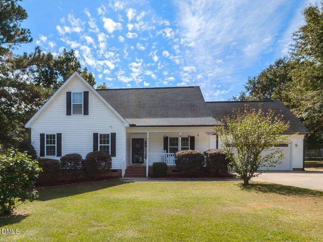 a front view of house with yard and trees in the background