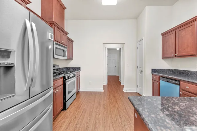 a kitchen with stainless steel appliances granite countertop a refrigerator a stove and a wooden floors