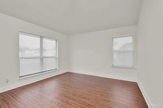 an empty room with wooden floor and window