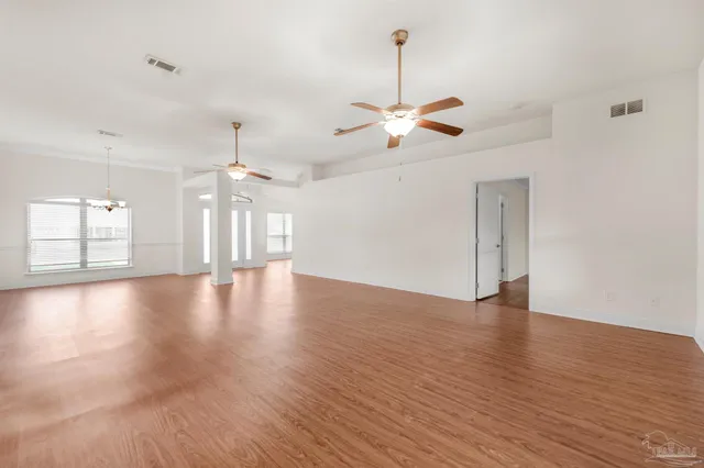 a view of an empty room with window and wooden floor