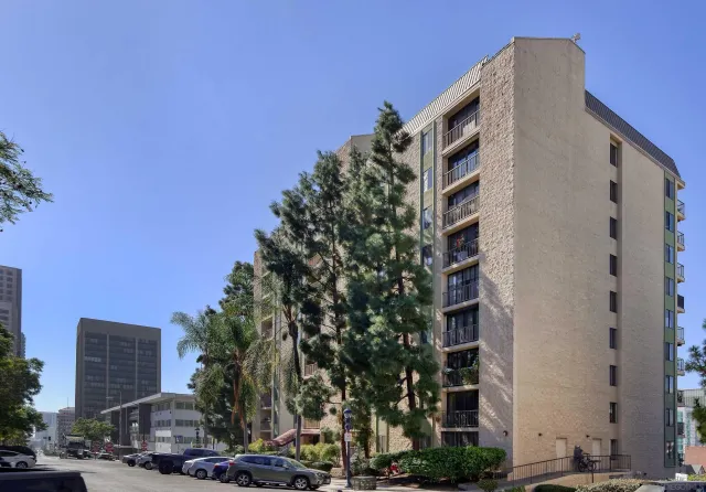 a front view of a building with lot of cars and trees