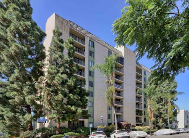 a front view of multi story residential apartment building with yard and parking space