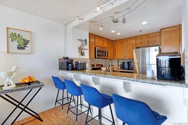 a kitchen with stainless steel appliances granite countertop a refrigerator a sink a stove a dining table and chairs