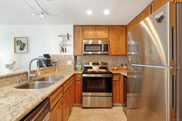 a kitchen with stainless steel appliances granite countertop a sink stove and refrigerator