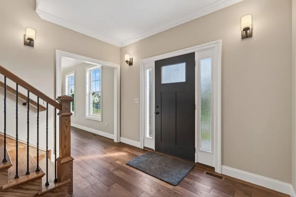 a view of an empty room with wooden floor fridge and a window