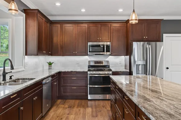 a kitchen with granite countertop stainless steel appliances a sink window and cabinets