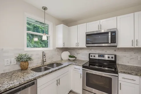 a kitchen with granite countertop a sink and a refrigerator