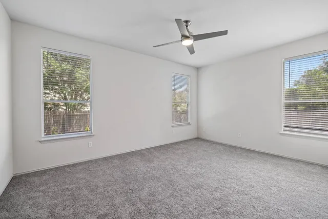 an empty room with windows and fan