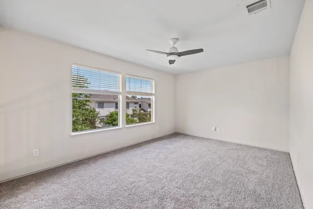 an empty room with windows and ceiling fan