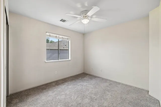 an empty room with windows and ceiling fan view