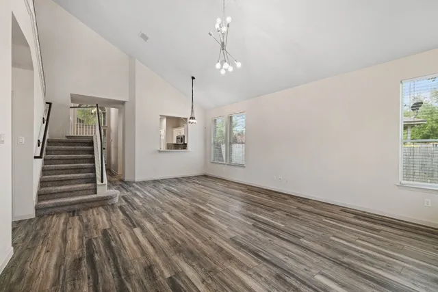 an empty room with wooden floor stairs and windows