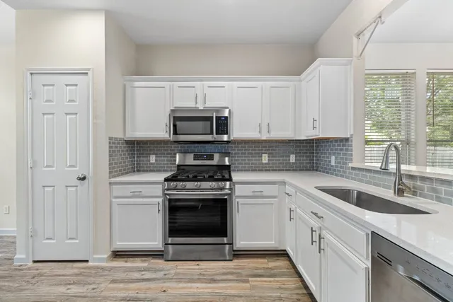 a kitchen with cabinets stainless steel appliances a sink and a window