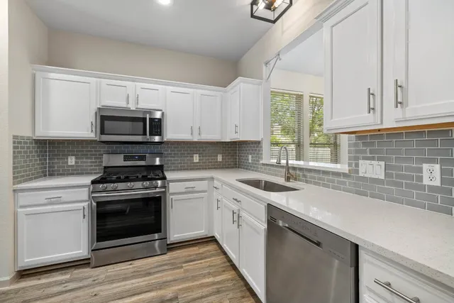 a kitchen with stainless steel appliances granite countertop a sink a stove a microwave and wooden cabinets