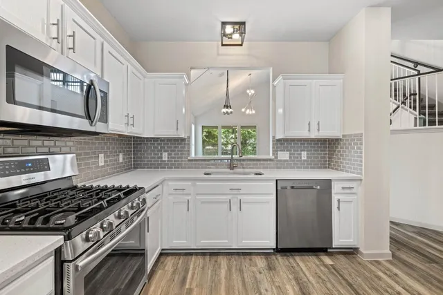 a kitchen with stainless steel appliances granite countertop a stove and a white cabinets