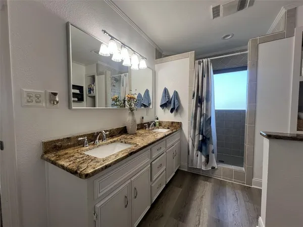 a bathroom with a granite countertop double vanity sink and mirror
