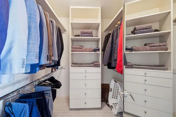 a view of walk in closet with clothes and shoes