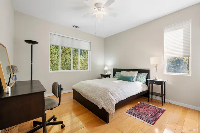 a bedroom with a bed a desk and chair with window