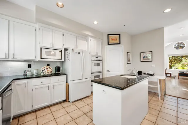 a kitchen with granite countertop white cabinets and refrigerator