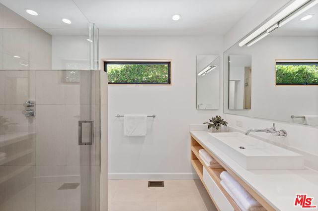 a bathroom with a double vanity sink a mirror and shower