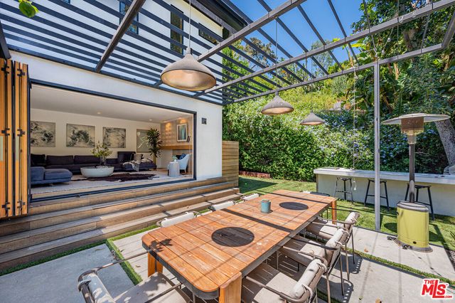 a view of a patio with table and chairs potted plants with floor to ceiling window and garden view