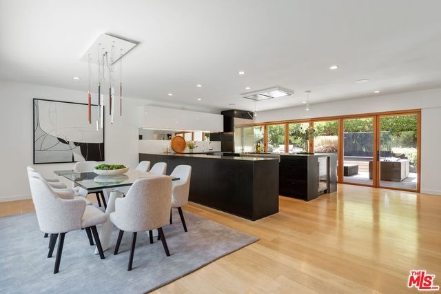 a dining hall with stainless steel appliances a dining table wooden floor a dining table and chairs