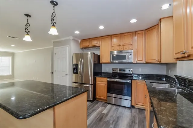 a kitchen with stainless steel appliances granite countertop a sink a stove and a refrigerator