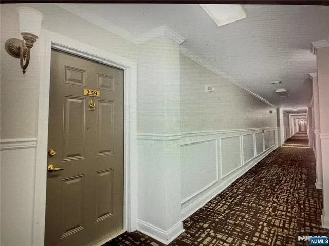 a view of a hallway with wooden floor and a bathroom