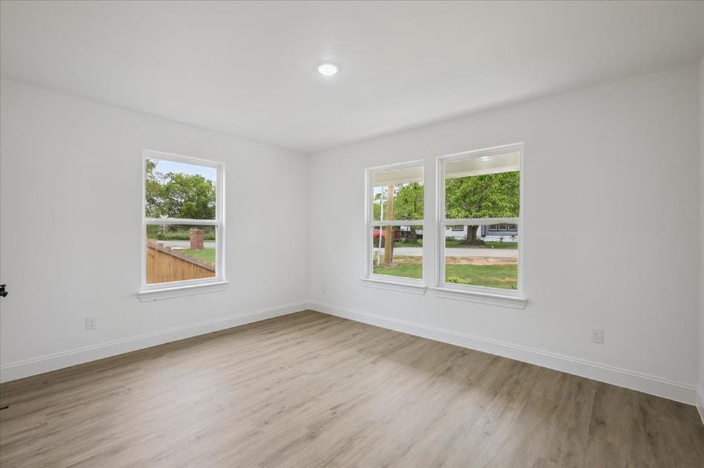 111 North Oak Street Ector, TX 75439 - Photo 17 of 34 an empty room with wooden floor and windows