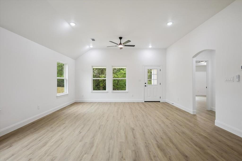 111 North Oak Street Ector, TX 75439 - Photo 20 of 34 an empty room with wooden floor chandelier fan and windows