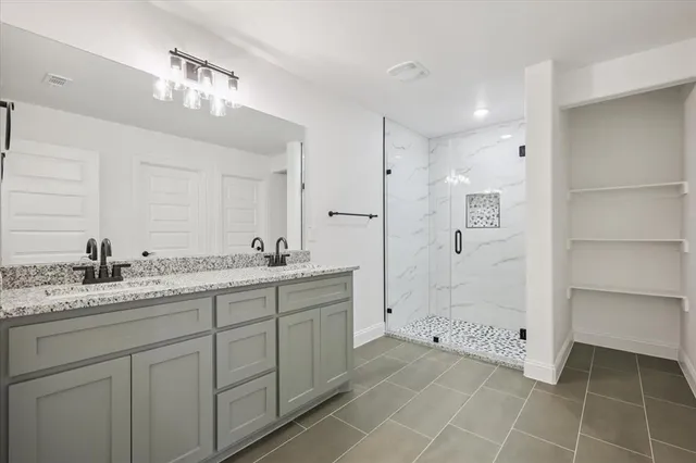 a spacious bathroom with a granite countertop sink a toilet a mirror and shower