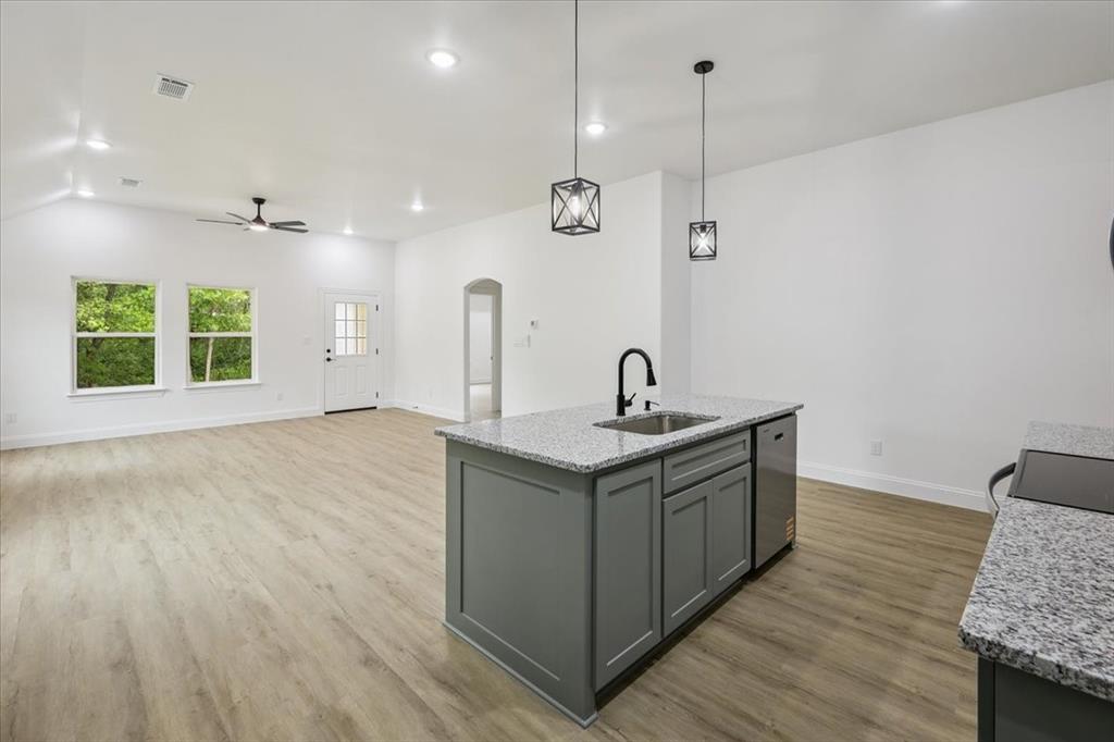 111 North Oak Street Ector, TX 75439 - Photo 10 of 34 a kitchen with stainless steel appliances granite countertop a sink a window and wooden floor