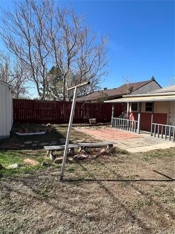 a view of a house with a yard chairs and wooden fence