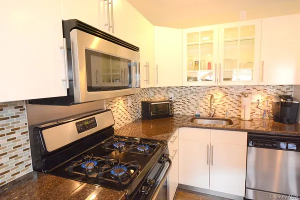 a kitchen with stainless steel appliances granite countertop a stove a sink and a microwave