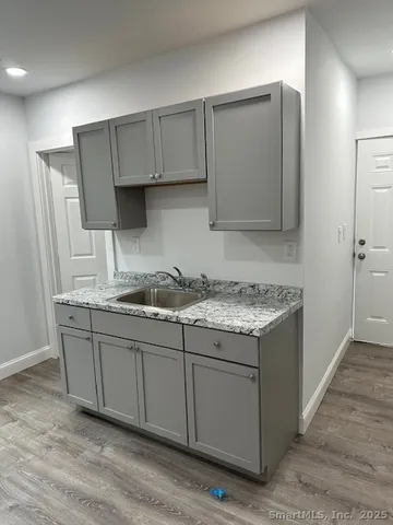 a kitchen with granite countertop a sink cabinets and wooden floor
