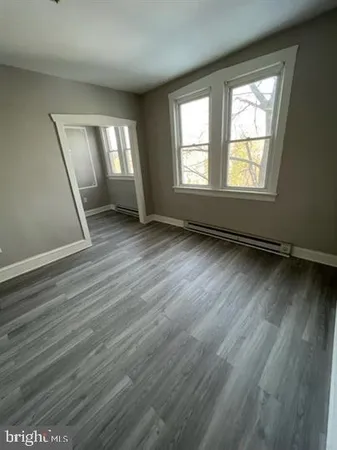 a view of an empty room with wooden floor and window