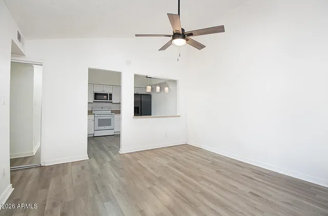 a view of a kitchen with wooden floor electronic appliances and a ceiling fan