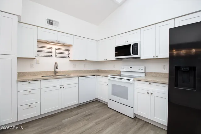 a kitchen with granite countertop white cabinets and black stainless steel appliances