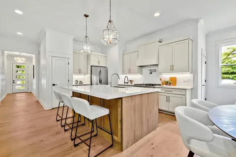 a kitchen with stainless steel appliances kitchen island granite countertop a table chairs sink and cabinets