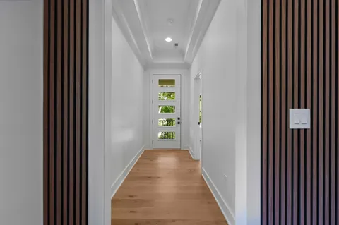 a view of a hallway with wooden floor and a bathroom