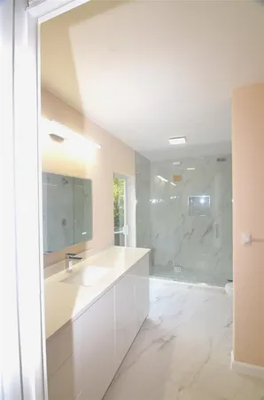 a large bathroom with a glass shower door and a sink