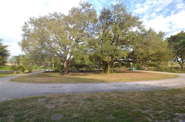 a view of a yard with wooden fence and large trees