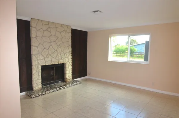 an empty room with windows and fireplace