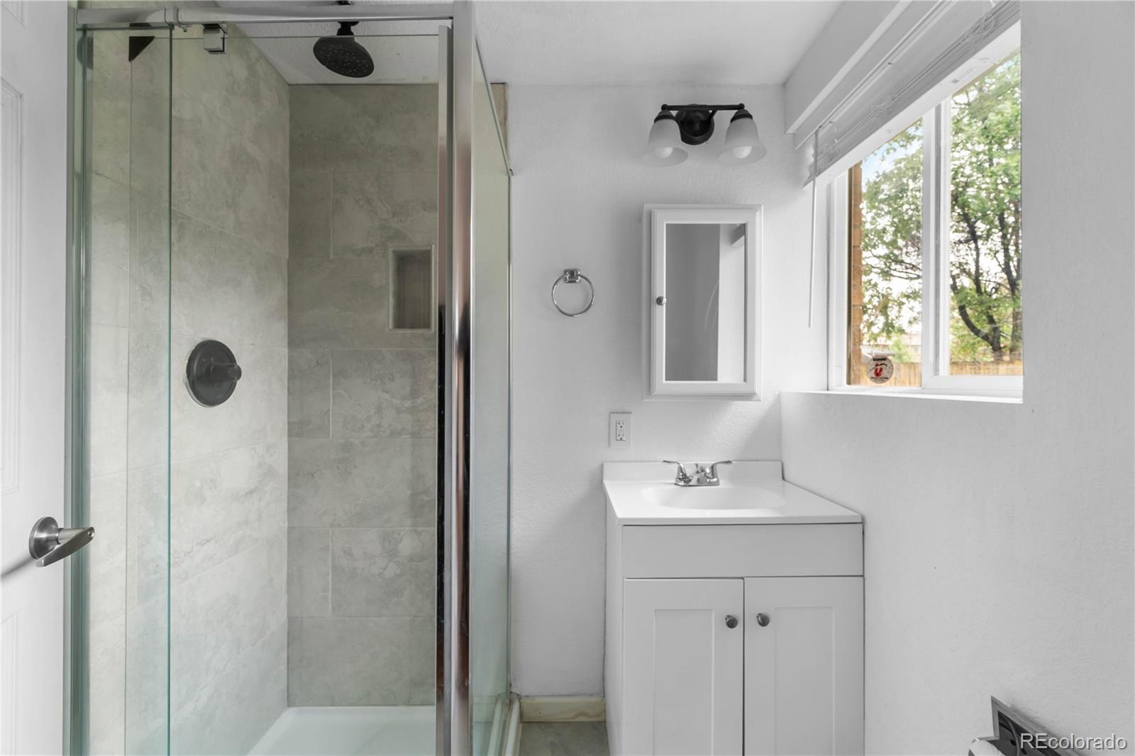 7010 West 44th Avenue Wheat Ridge, CO 80033 - Photo 18 of 31 a bathroom with a sink a mirror and shower
