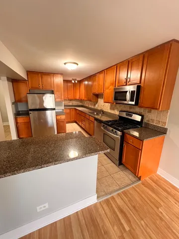 a kitchen with stainless steel appliances granite countertop a sink wooden cabinets and a granite counter top