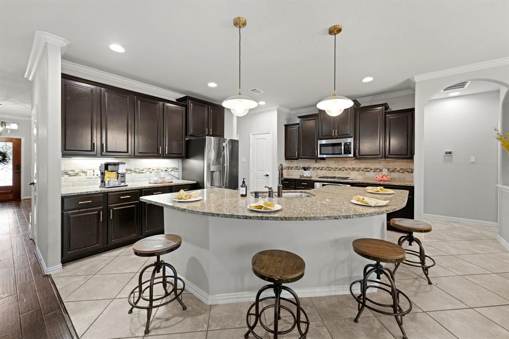 a kitchen with stainless steel appliances kitchen island granite countertop a stove a refrigerator a kitchen island a sink with a dining table and chairs