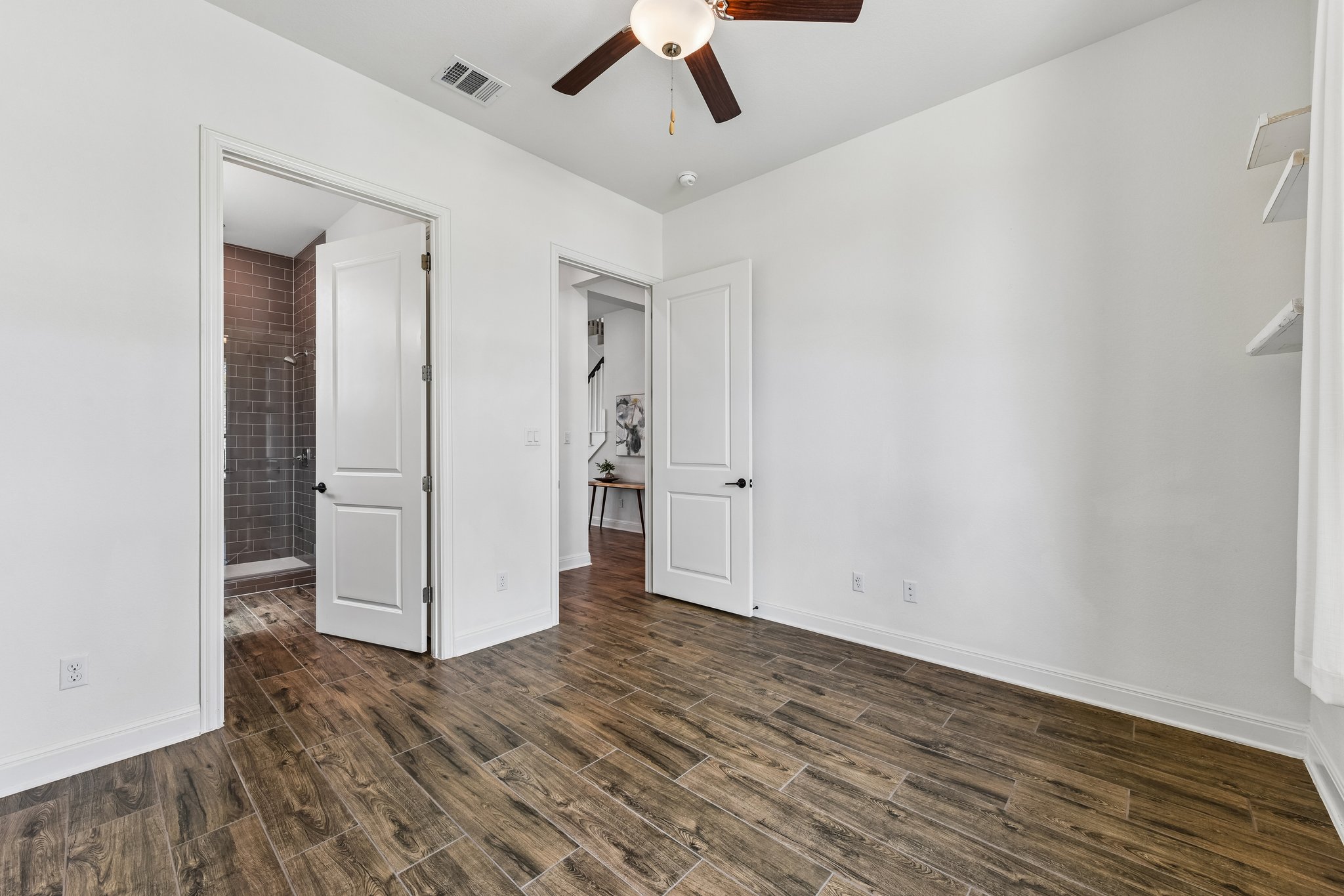 19113 Freeman Circle Austin, TX 78738 - Photo 18 of 37 A well-appointed bedroom featuring rich wood-look flooring and a connecting private bath with tiled shower.