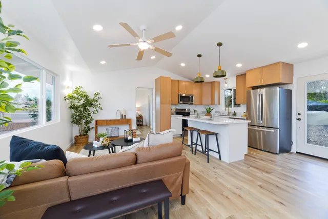 a living room with kitchen island furniture wooden floor and a kitchen view