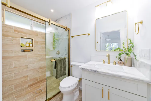 a bathroom with a granite countertop sink a toilet and shower